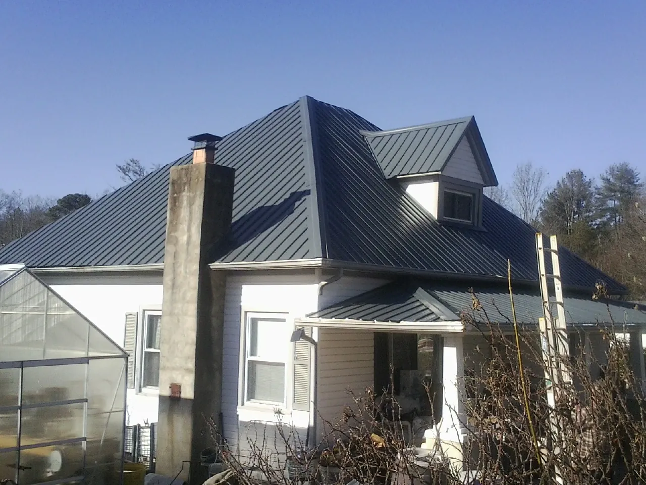 Dark blue standing seam metal roof on a white farmhouse with dormer — Slate & Tile Roof Repair by Roofing Brothers in Dugway