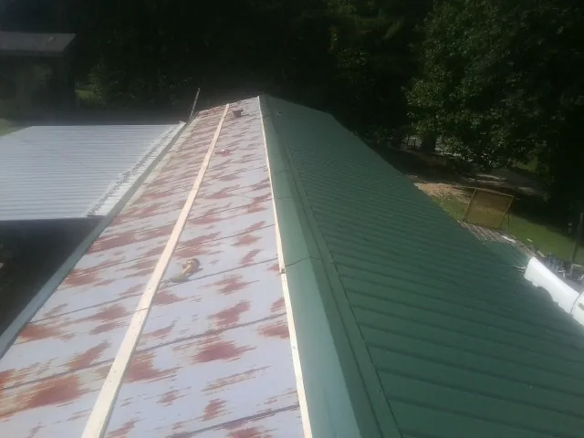 Old rusted panels beside newly installed green metal roofing — Wind Damage Roof Repair by Roofing Brothers in Dugway