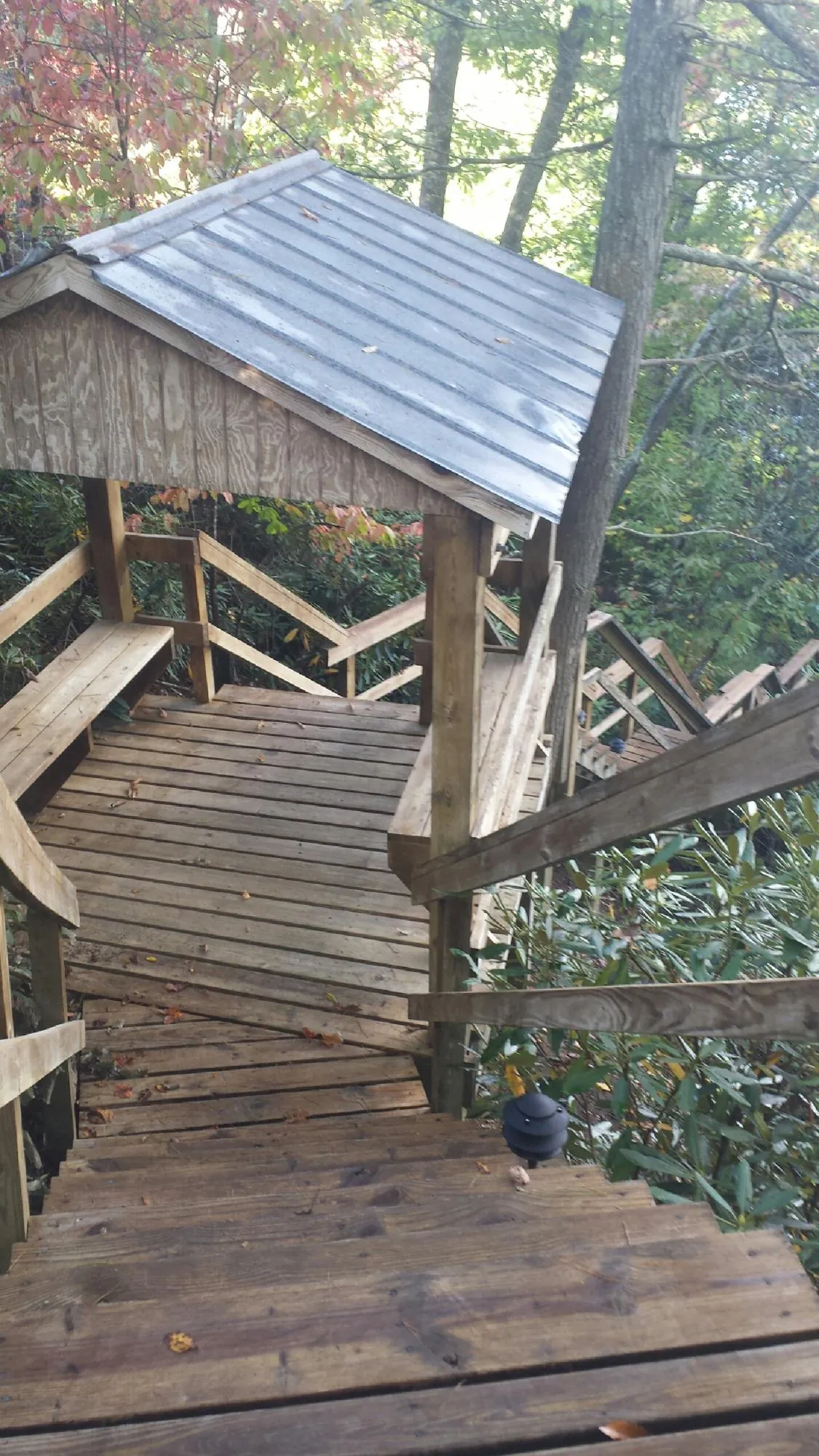 Metal roofed shelter over wooden steps on a wooded walkway — Skylight Repair & Installation work by our crew in Dugway
