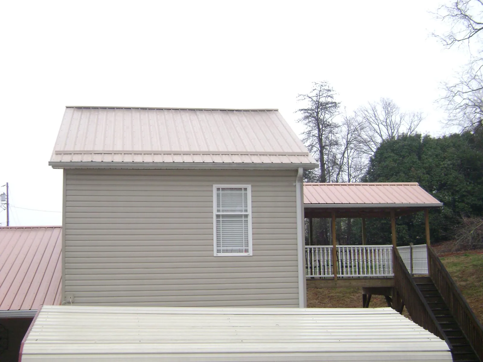 Tan metal roofs on a two story addition and attached porch, from a Roof Replacement job in Dugway